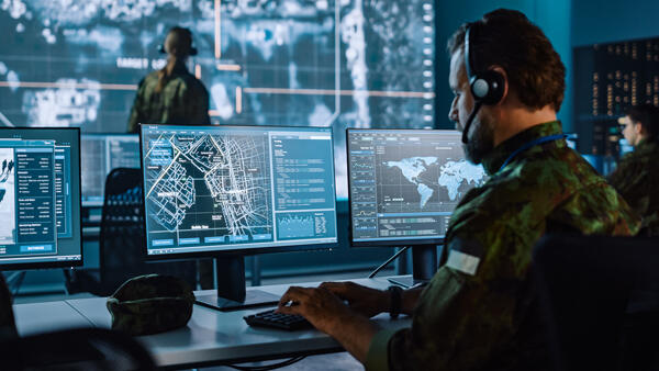 Military control room operator looking at monitors and video wall